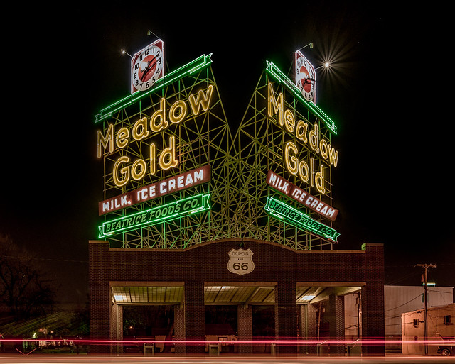Iconic Meadow Gold Neon sign on Route 66 with a few car light trails