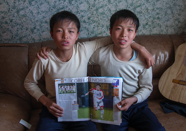 Portrait of North Korean twins holding a french football magazine, North Hamgyong Province, Jung Pyong Ri, North Korea