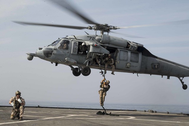 U.S. Marines fast-rope onto the flight deck during a simulated visit, board, search, and seizure mission aboard USS Rushmore.