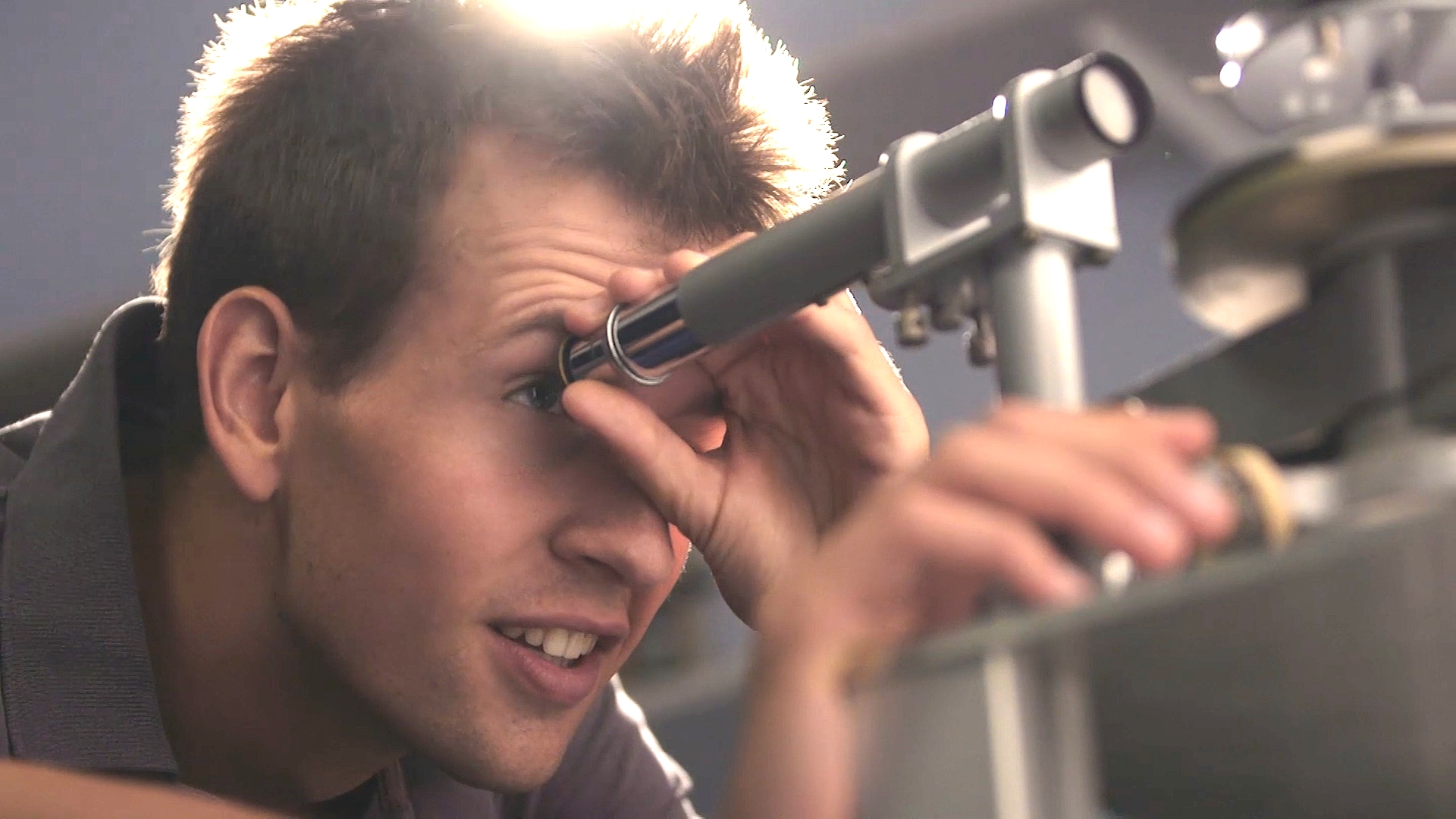 Male student looking through a long metal tube - physics equipment