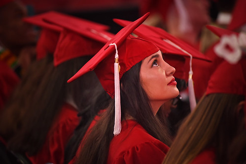 Graduate watches the guest speaker on the jumbtron in PNC Arena.