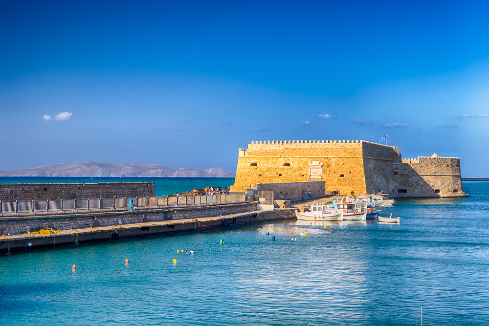 Koules Fortress and Old Venetian Harbour with Lines of Sailing Fishing Boats At Noon in Heraklion City, Greece.