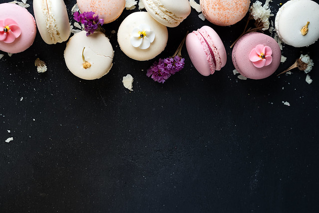 Colorful macarons on black stone background. Top view with copy space.