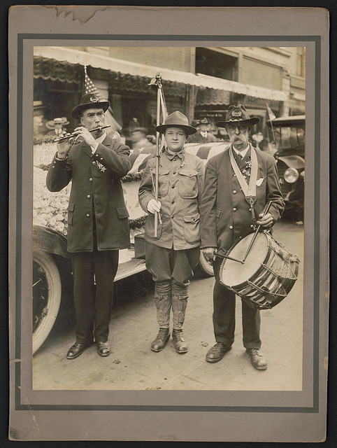 [Civil War veterans in Grand Army of the Republic uniforms playing fife and drums with Boy Scout holding flag in front of decorated car] (LOC)