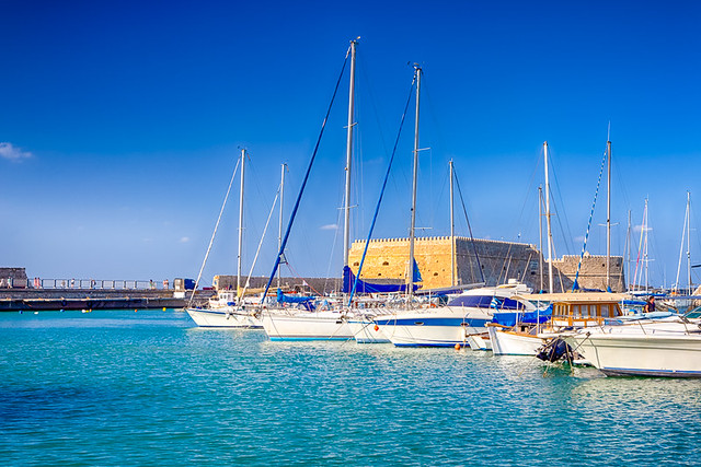 Koules Fortress and Old Venetian Harbour with Lines of Sailing Fishing Boats At Noon in Heraklion City, Greece.