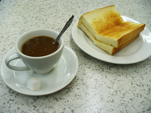 cup of coffee next to buttered toast in a breakfast cafe