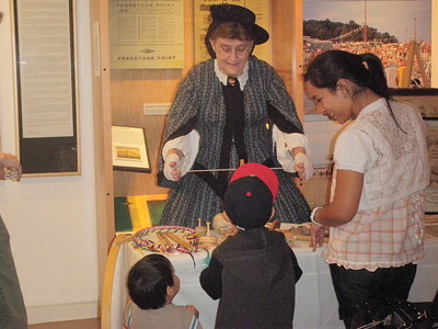 lady dressed in colonial grab demonstrating game to children