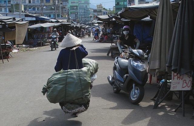 Vietnamese woman carrying a traditional don ganh (yoke)