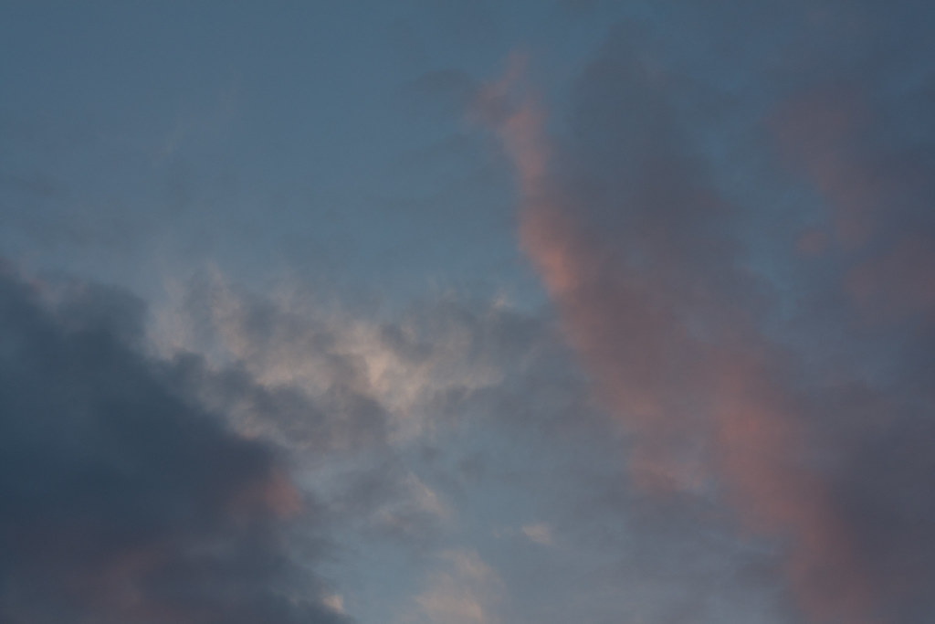 Pastel sunset sky filled with soft pink, lavender, and slate gray clouds drifting across a fading twilight blue.
