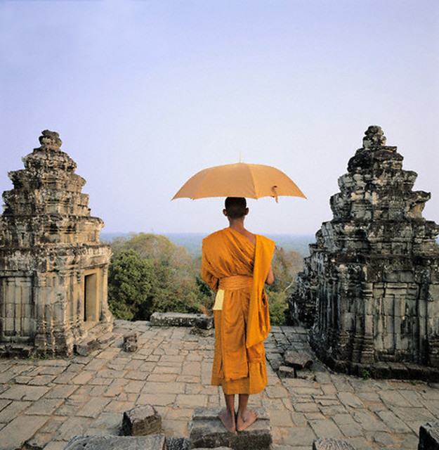 Monk with umbrella standing atop Angkor Wat