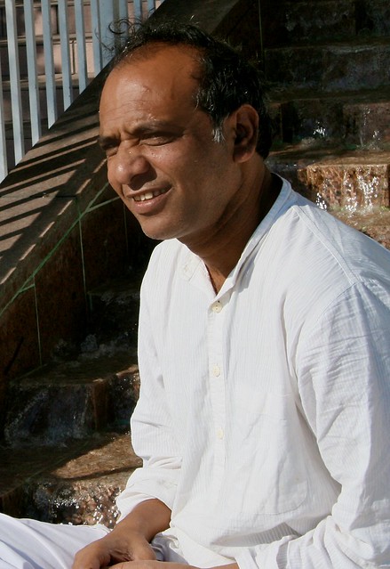 Indian man seated by water feature