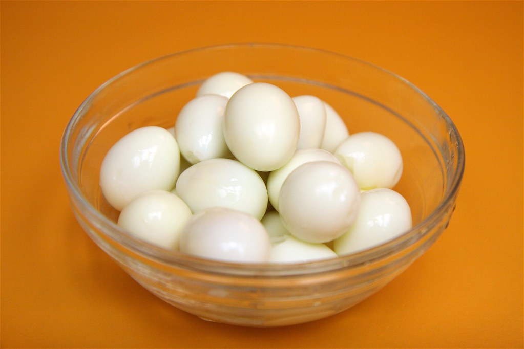 a bowl of white eggs on a orange background - Hard Boiled Quail Eggs