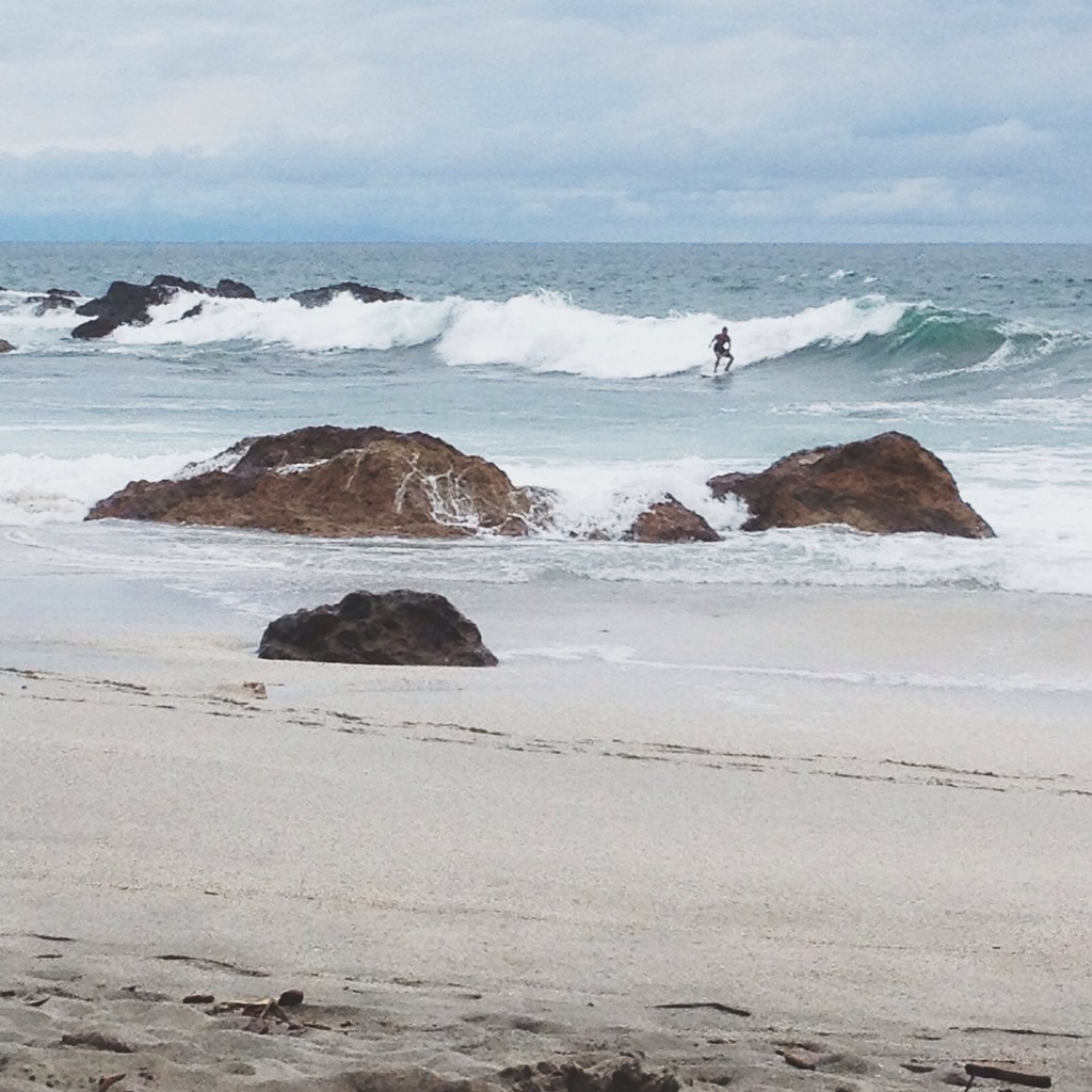 Solo surfer riding a wave between rocks