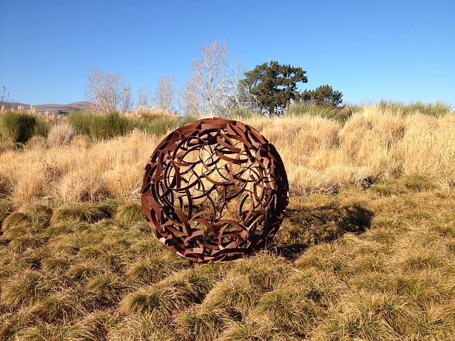 Weathering Steel Sphere laying in pasture at Cornerstone Garden in Sonoma CA