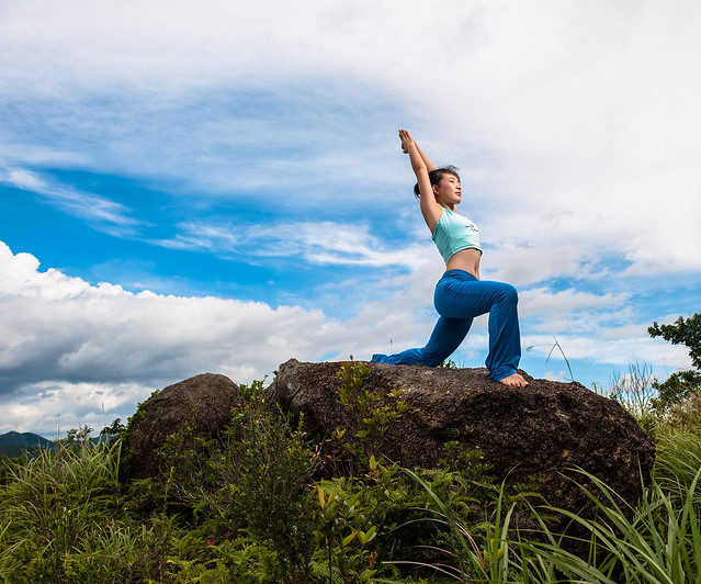 woman practicing yoga on top of rock formation