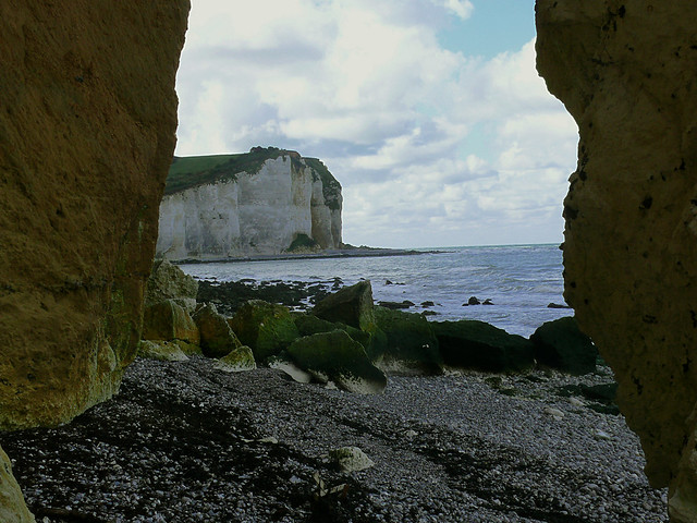 2007.09 -  'A see-through view between two ocher-colored rocks', on the steep cliffs on the shore of Petit-Dalle in Normandy France under a blue-white sky; French landscape photography, Fons Heijnsbroek