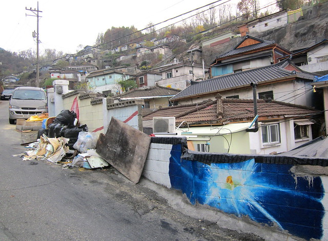 Seoul Korea hillside ant village slum shanty area with colorful murals dukeing it out with cluttered junk - 