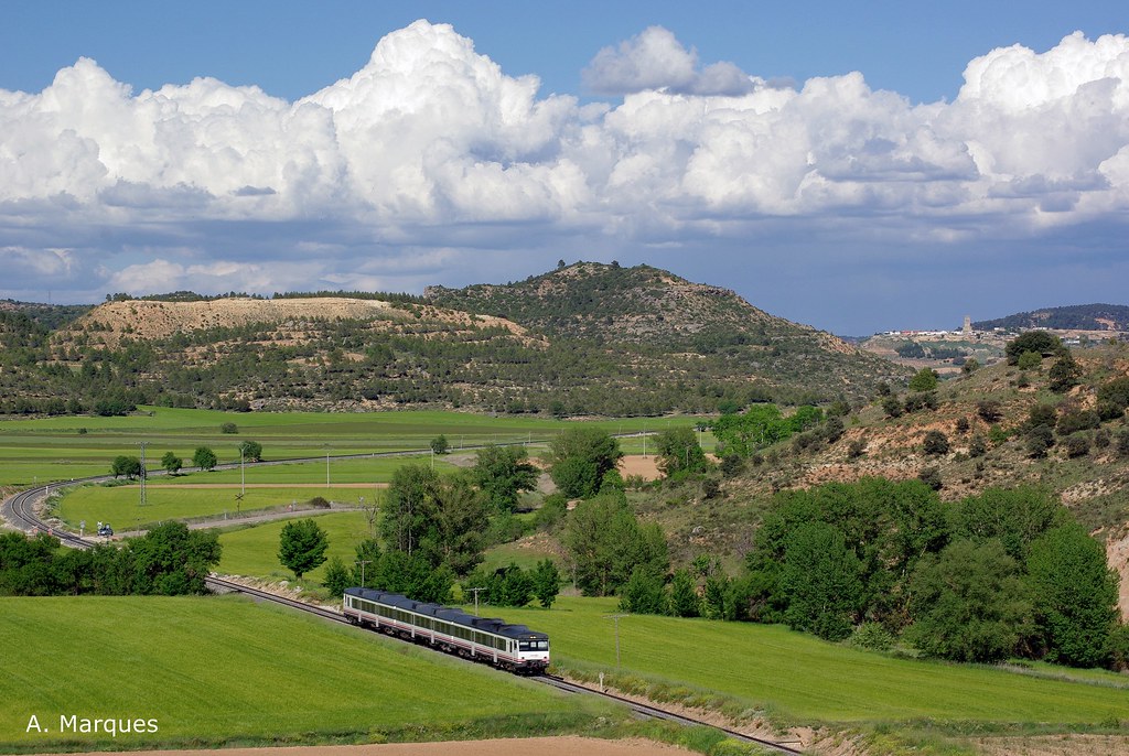 Green fields and a low hillside beside a railway