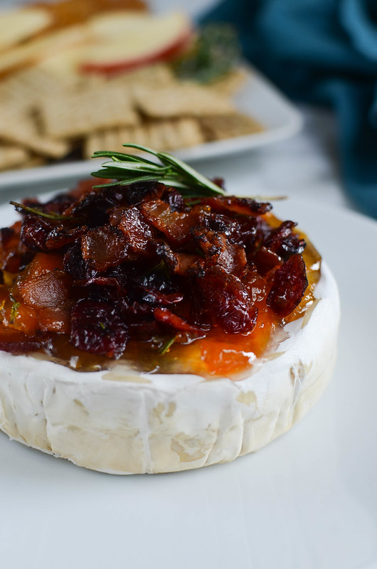 Bacon Cranberry Baked Brie - the perfect holiday appetizer! Brie topped with bacon, dried cranberries, apricot preserves, fresh rosemary and then baked until melty and delicious. 