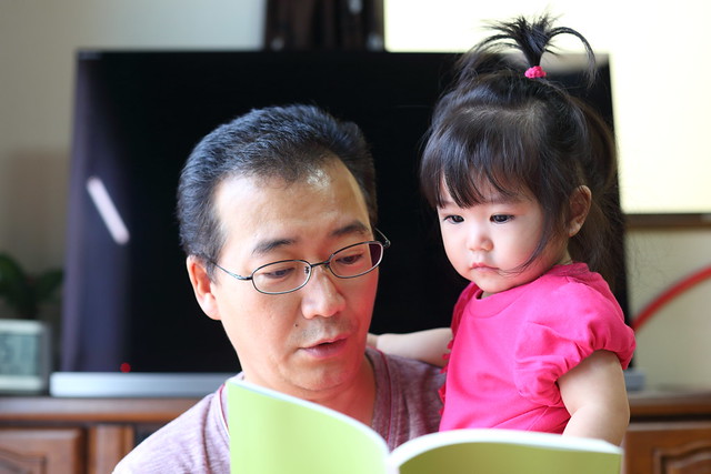 a Man reading a book to his child