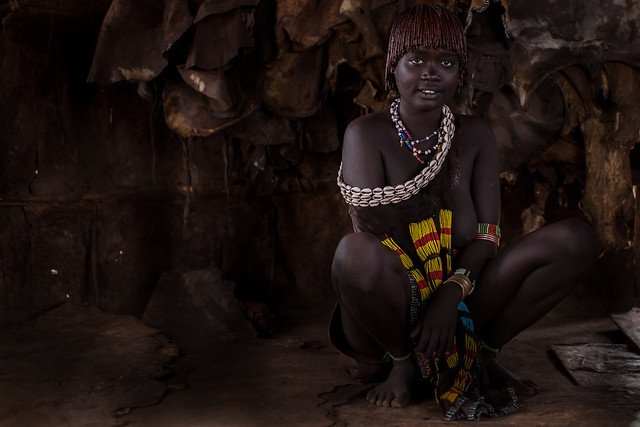 Portrait of girl tribe Hamer inside the hut with the backdrop of animal skins