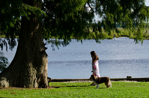 Photo of woman and dog walking along waterside trail