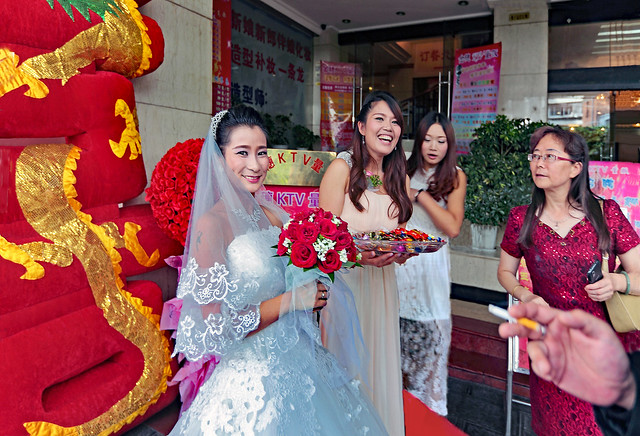 China 2014. Kunming (Yunnan). The bride holding a roses bouquet and offering candies …