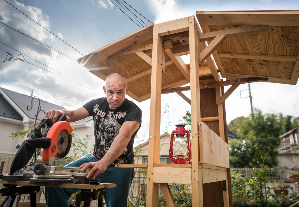 A homeowner cuts a wooden board with a circular saw on a workbench in a tidy garage workshop. A homeowner cuts a wooden board with a circular saw on a workbench in a tidy garage workshop.