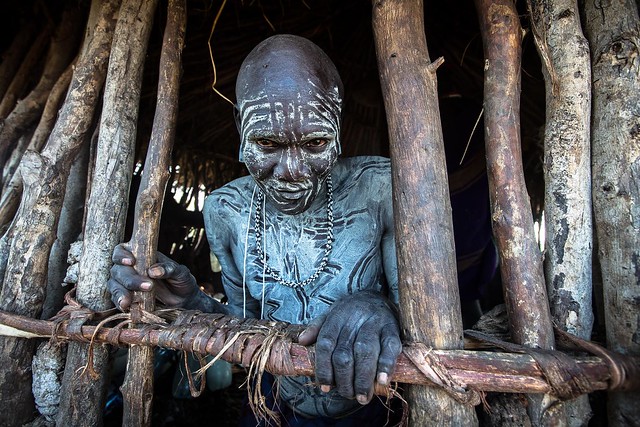 Mursi tribe warrior waking inside the hut