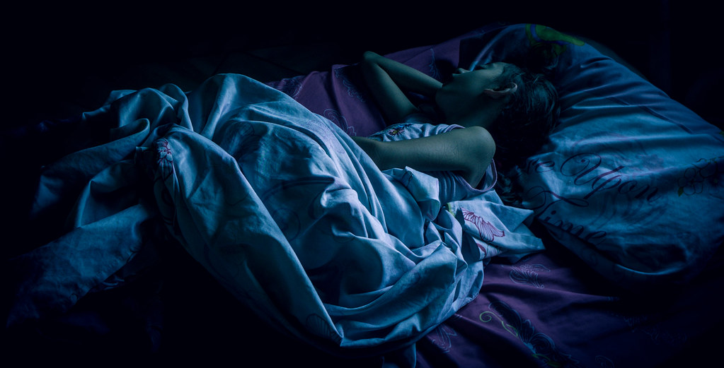 Под одеялом сестренкой. Сон в темноте. Девушка в кровати ночью.