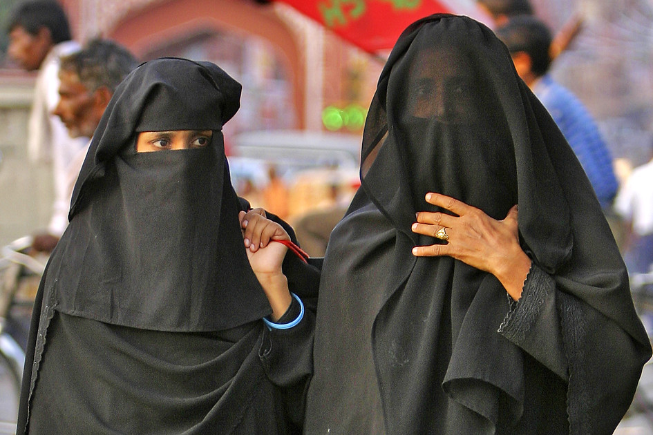 Mujer musulmana con hijab negro y ropa oscura caminando por el edificio  gris de la ciudad. la dama con expresión divertida representa el espacio de  copia de la cultura islámica.