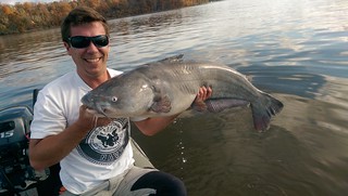 Photo of man holding a large blue catfish he caught