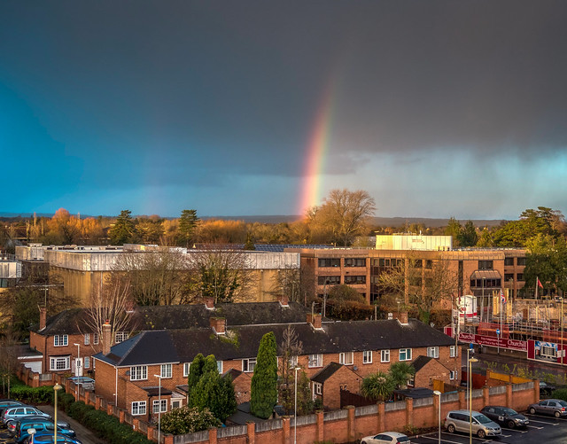 A rainbow behind Andover Leisure Centre in Hampshire as rainclouds pass through at sunset