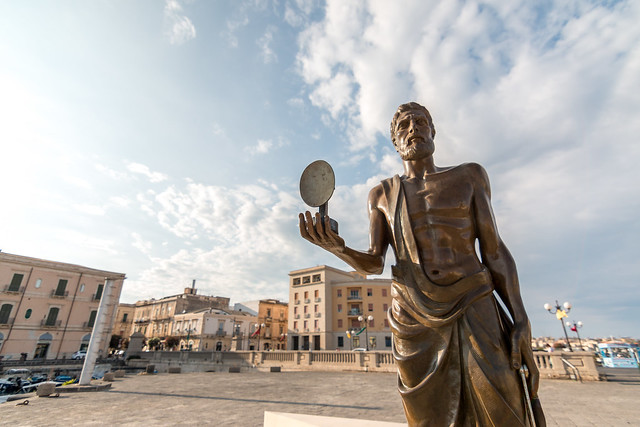 Archimedes with the heat ray mirror protects the seaport of Ortigia.