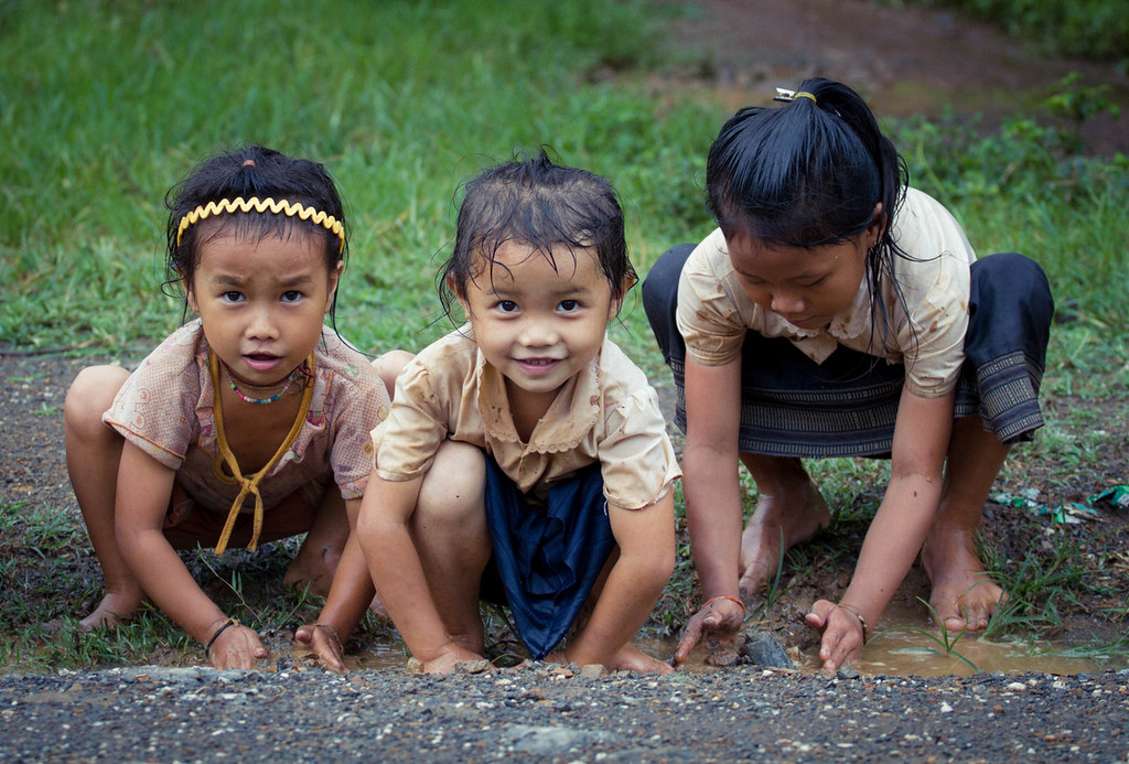 Haciendo presas Three Hmong girls play with water after th. 