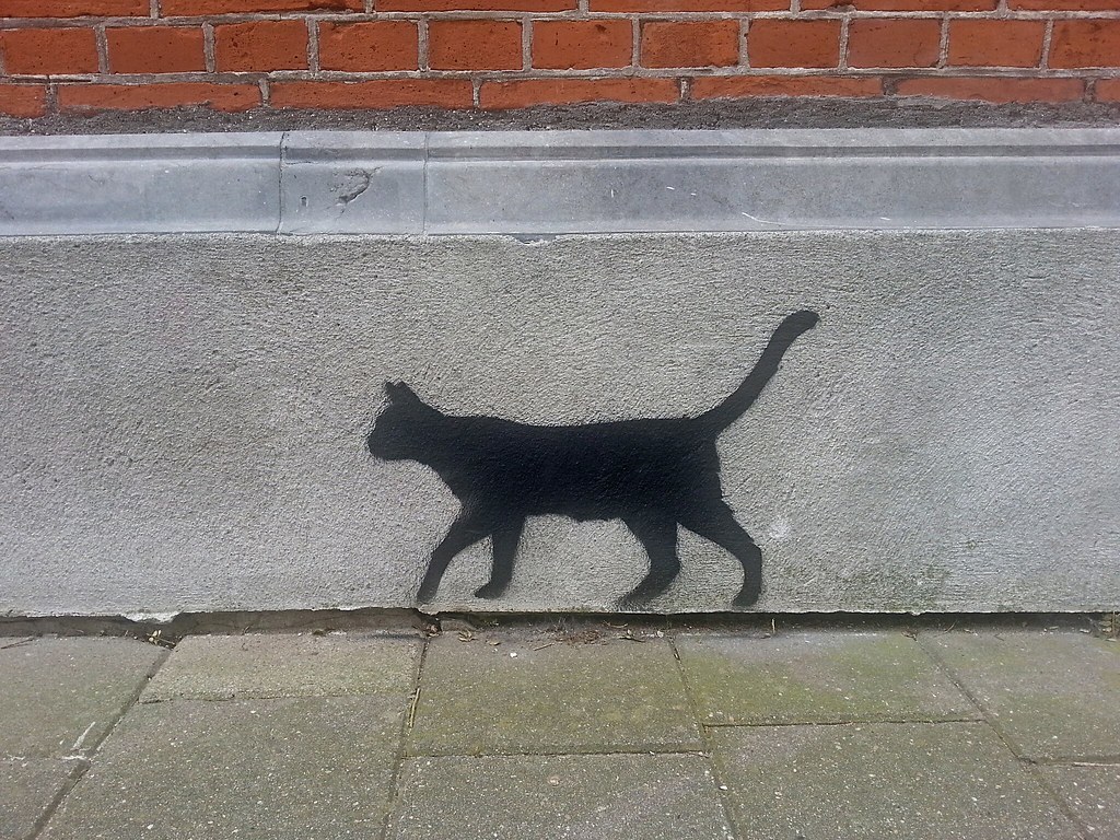 Gemalte schwarze Katze an einer Hauswand.