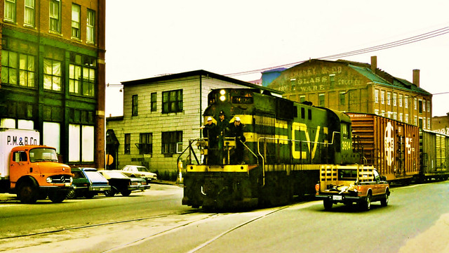 Central Vermont 3604 (Alco RS11) snakes through traffic with a train at Center & Commercial Streets in Portland ME on 9-13-1982