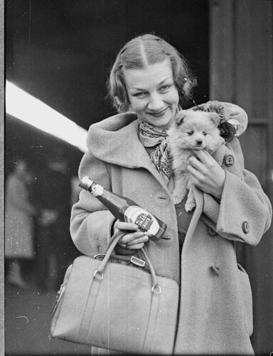 Ballet star Helene Kirsova with puppy and tomato sauce bottle on arrival back in Sydney for a return season, Central Railway Station, May 1937 / Sam Hood | by State Library of NSW