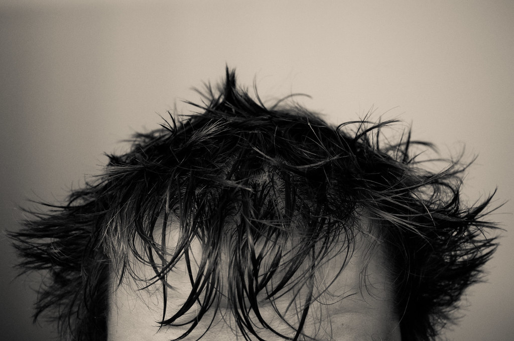 Black and white close-up portrait focusing on wet, spiked dark hair against a neutral background.