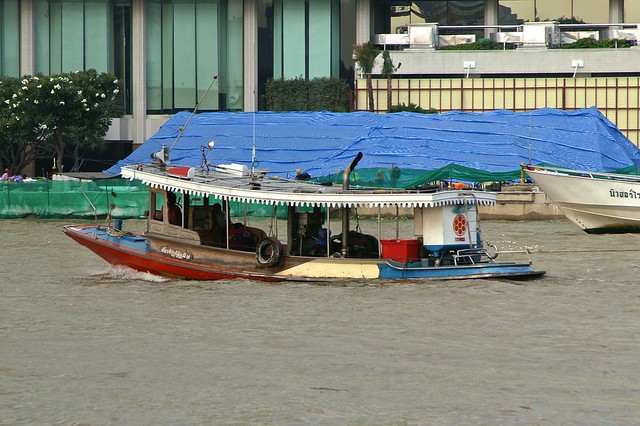 Tug boat on the Chao Phraya river in front of the Shangri-La Hotel in Bangkok, Thailand