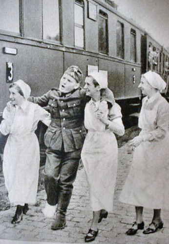 Three German Red Cross nurses helping a wounded German soldier at a railway station