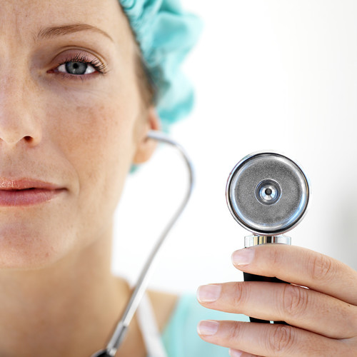 Female Doctor Wearing Protective Headgear and Using Stethoscope --- Image by © Royalty-Free/Corbis | by socolunistas