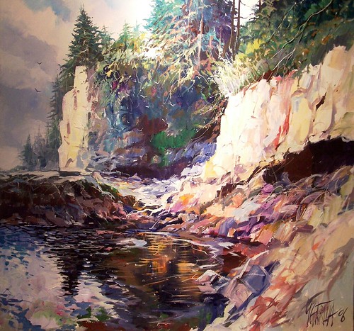 Sunlit rocky beach beneath forested cliffs