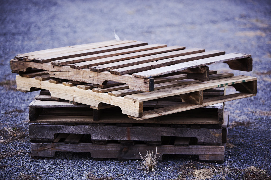 Two wooden pallets stacked in a parking lot.