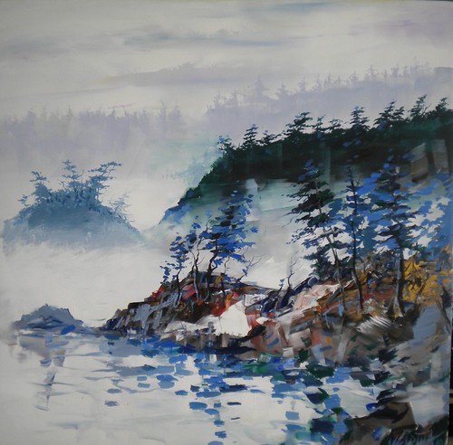 Misty rocky shoreline with dark evergreens