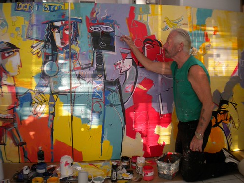 Artist standing beside a wide figurative painting