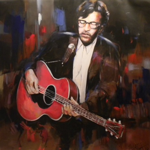 Seated guitarist with a red acoustic guitar