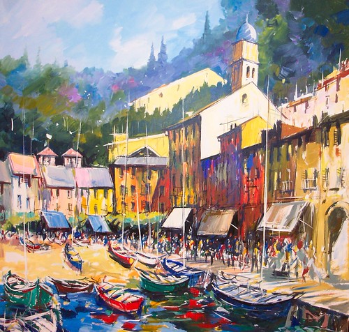 Boats below pale harbour buildings and green hills