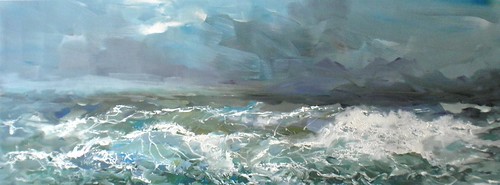 Breaking ocean waves beneath a cloudy sky