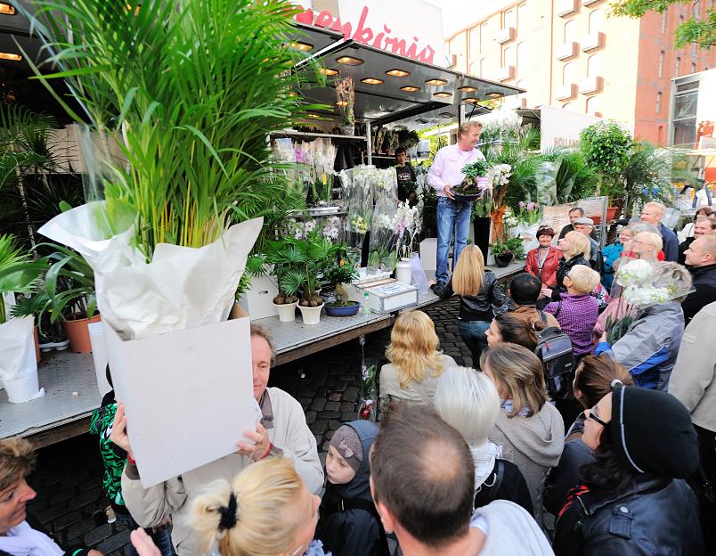 6944 Pflanzenverkauf auf dem Fischmarkt in Hamburg - ein Marktbesucher hat mehrere Palmen erstanden und trägt sie im Karton davon.